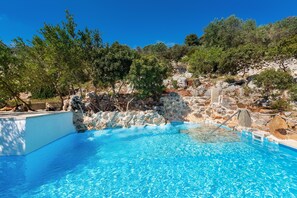 A clear blue pool surrounded by rocky terrain and trees. - Il Giardino delle Cipolliane (Gagliano del Capo)