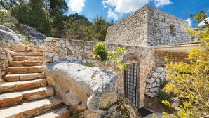 A stone building with a small entrance and a staircase leading up to it. - Il Giardino delle Cipolliane (Gagliano del Capo)