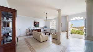 A spacious living room with a sofa, armchairs, a wooden cabinet, and a large window offering a view of the outdoors. - 619 La Ripostiera by Barbarhouse (Castro)