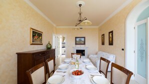 A dining room with a long table set for six, flanked by wooden chairs, a fireplace, and framed artwork on the walls. - 619 La Ripostiera by Barbarhouse (Castro)