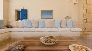 A cozy living room with a beige sofa, a wooden coffee table with decorative items, and a blue door in the background. - Lo Scoglio Bianco (Ostuni)