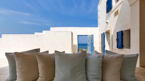 A white building with blue shutters and a view of the sea. - Lo Scoglio Bianco (Ostuni)