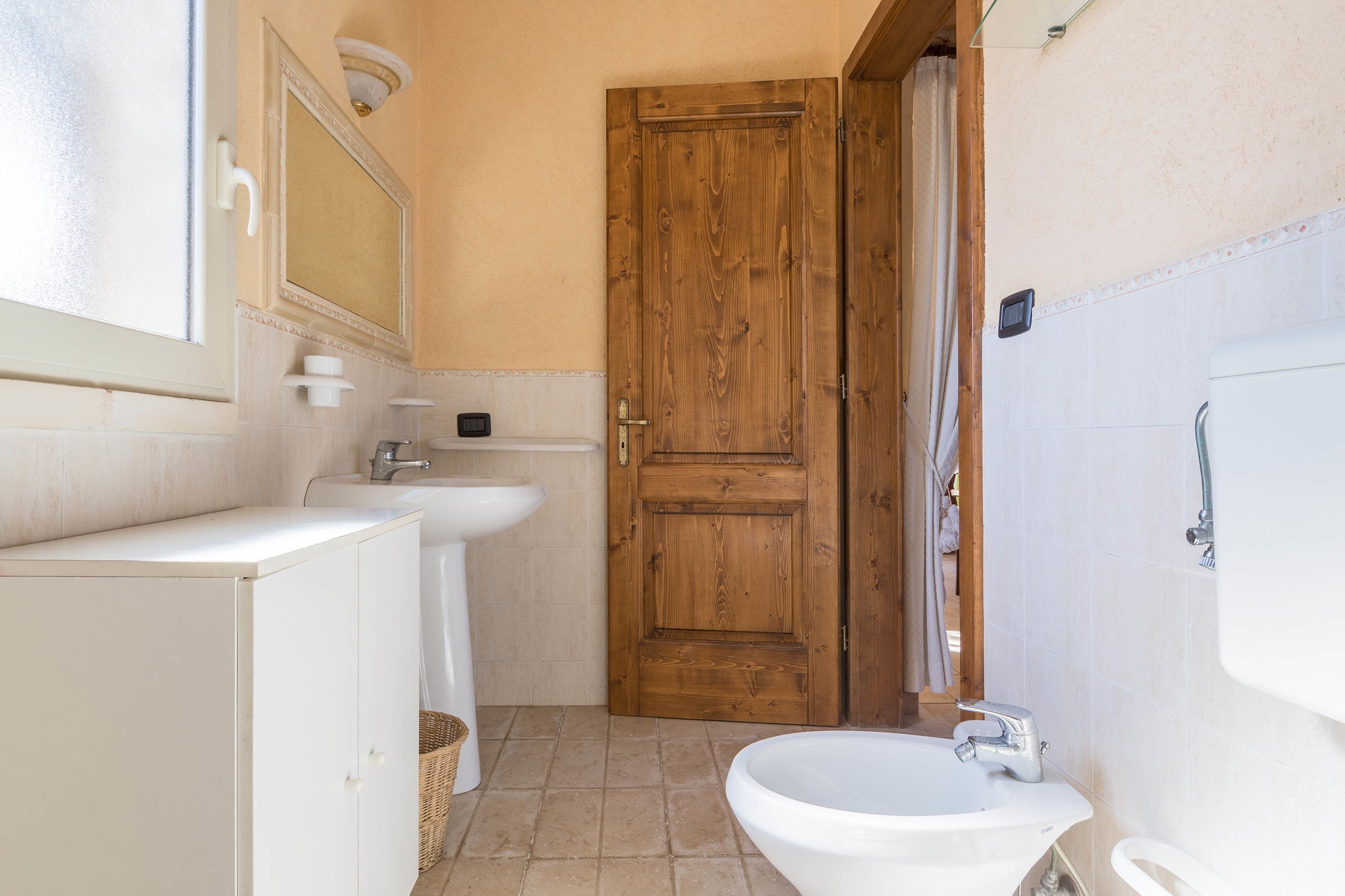 A bathroom with a wooden door, a white sink, and a white toilet.