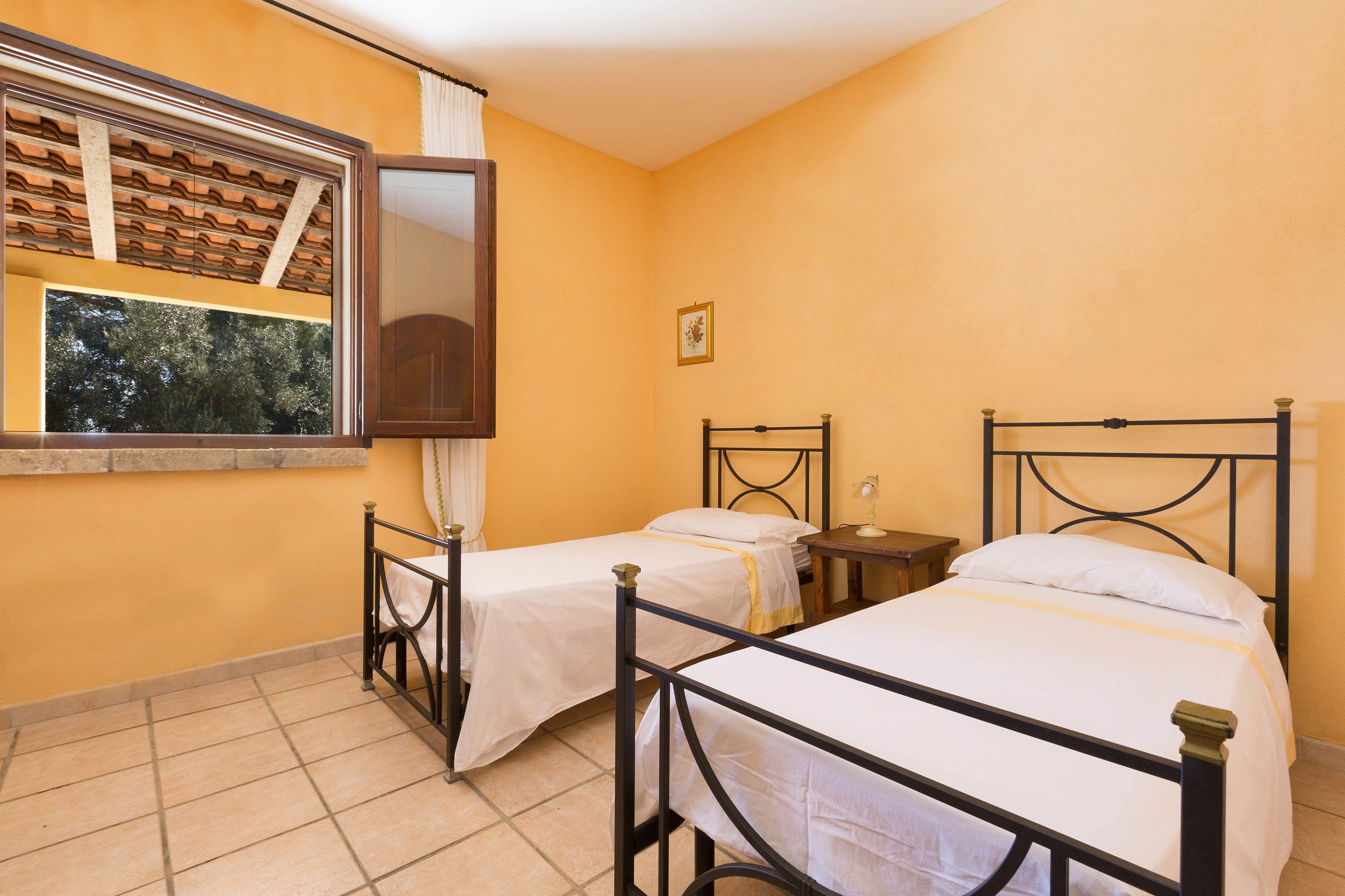 Une chambre avec deux lits, une fenêtre donnant sur la forêt et une petite table avec une lampe.