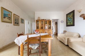 A dining area with a wooden table and chairs, a cabinet with glass doors, and a beige sofa.