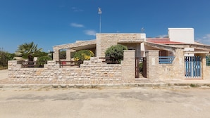 A stone building with a red-tiled roof, a satellite dish, and a gated entrance. - 937 Riva del Conte by Barbarhouse (Porto Cesareo)