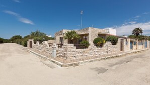 A stone building with a flat roof, a satellite dish, and a small garden. - 937 Riva del Conte by Barbarhouse (Porto Cesareo)