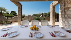 An outdoor dining area with a table set for four, surrounded by brick walls and white chairs. - 937 Riva del Conte by Barbarhouse (Porto Cesareo)