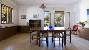 Un comedor amplio con una gran mesa de madera y seis sillas, una lámpara colgante y vistas al exterior a través de una puerta.