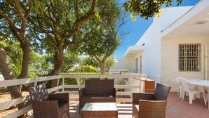 Un patio exterior con muebles de mimbre y una cerca blanca.