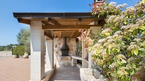Un espace extérieur aménagé en terrasse, avec des colonnes en pierre, une cheminée en pierre et une pergola en bois.