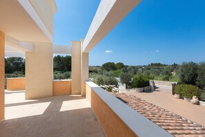 An outdoor balcony with a tiled floor, white columns, and a view of the countryside. - Sogno d`Itria (Villa Castelli)