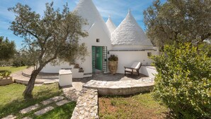 Un edificio blanco con techos cónicos, una puerta verde y un camino de piedra que conduce a un área de descanso.