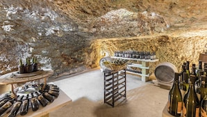 An underground wine cellar with stone walls, wine racks, and bottles. - Trulli Ion (Ostuni)