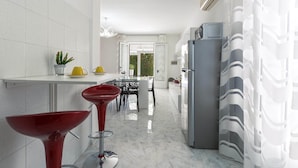 Eine moderne Küche mit Marmorarbeitsplatte, einem roten Barhocker und einem grauen Kühlschrank.