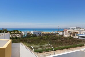 A coastal view with a beach, umbrellas, and buildings.