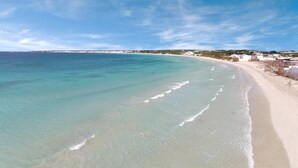 Ein Strand mit klarem türkisfarbenem Wasser und einem sandigen Ufer.