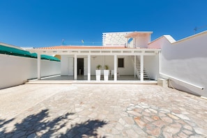 A courtyard with a stone floor, white walls, and a tiled roof.
