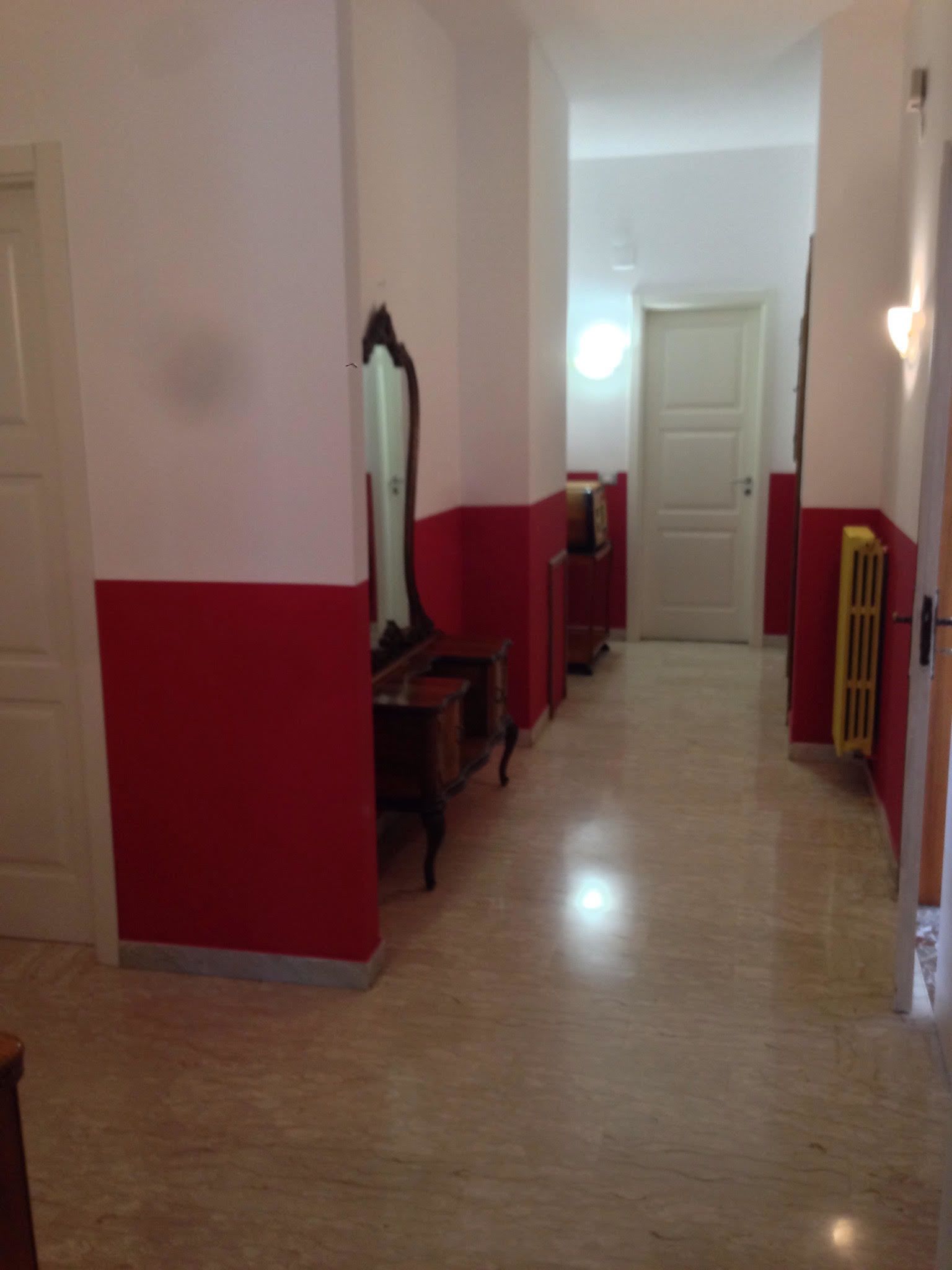 A hallway with a red and white color scheme, a mirror, and a radiator.