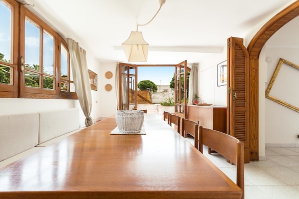 Un coin repas avec une longue table en bois, des chaises et un panier en osier.