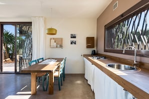 Una cocina compacta con una mesa y sillas de madera, un ventanal con vistas y un lavamanos con grifo moderno.
