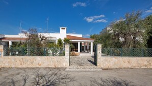 Una casa con entrada de pared de piedra, un porche cubierto y un cielo azul claro.