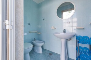 A bathroom with a toilet, bidet, and pedestal sink.