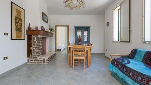 Amplia sala de estar con chimenea, una mesa de comedor con sillas, un sofá y un ventanal grande.