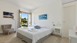 Un dormitorio moderno con cama, una silla, un escritorio y vistas al exterior.