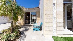 A house with a patio, a blue chair, and a small garden. - Villetta Giorgina (Porto Cesareo)