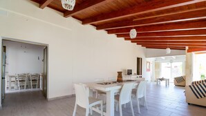 A spacious living area with a wooden ceiling, a dining table with chairs, and a sofa. - Villetta Giorgina (Porto Cesareo)