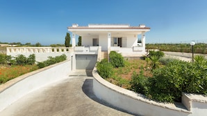 A white villa with a tiled roof, a covered porch, and a curved driveway. - Villetta di Paulo (Carovigno)