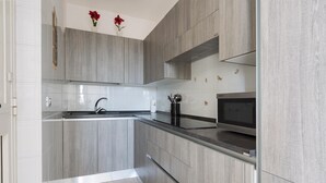 A modern kitchen with grey cabinetry, a stainless steel sink, and a built-in microwave. - Villetta di Paulo (Carovigno)