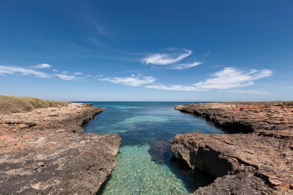 A rocky coastal landscape with clear blue waters and a clear sky.