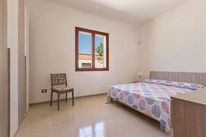A bedroom with a bed, a chair, a window, and a view of the outside.