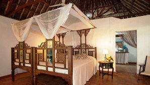 A four-poster bed with a canopy, a bedside table with a lamp, and a chair. - Diani house (Diani Beach)