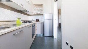 Een moderne keuken met witte kasten, een roestvrijstalen koelkast en een aanrecht met een waterkoker.