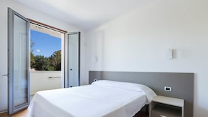 Een slaapkamer met een bed, een nachtkastje en een schuifdeur naar een buitenruimte.