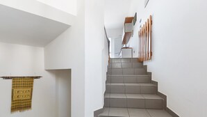 A staircase with grey tiles and wooden handrails, leading to a landing with a white wall and a hanging tapestry. -  909 Appartamento Porticciolo by Barbarhouse (Porto Cesareo)