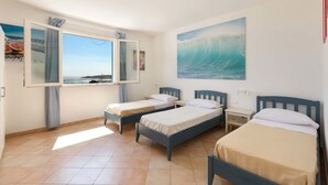 A room with two beds, a window with curtains, a painting of a wave, and a tiled floor. - Attico del Blu (Castrignano del Capo)