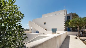 A modern building with white walls and blue accents, featuring a balcony and a tree in the foreground. - Attico del Blu (Castrignano del Capo)