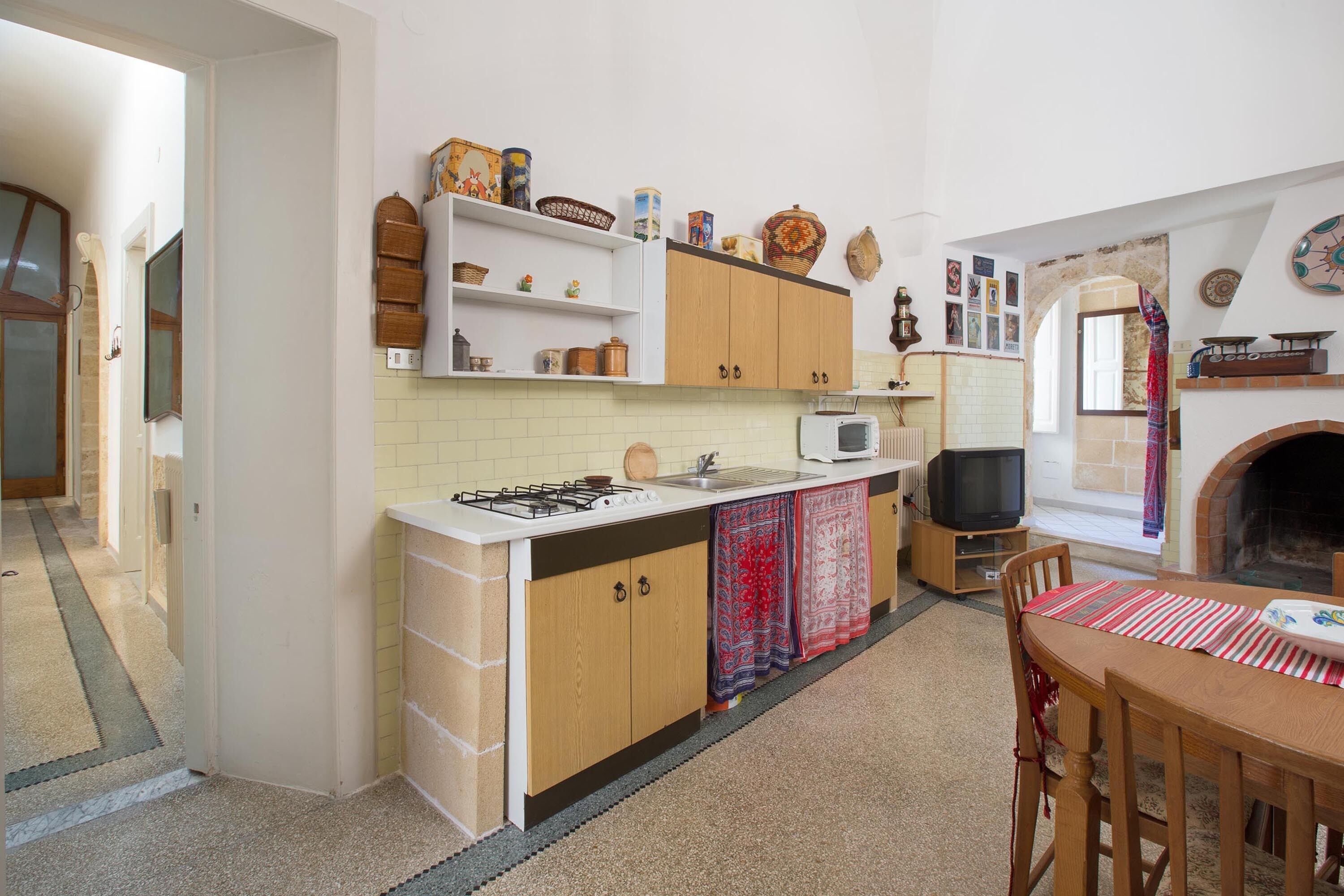 A compact kitchen with a gas stove, microwave, and a small dining table with chairs.