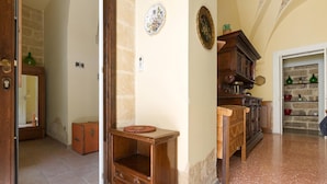 A hallway with a wooden cabinet, a door, and a wall-mounted plate. - Casa Messapica (Ugento)