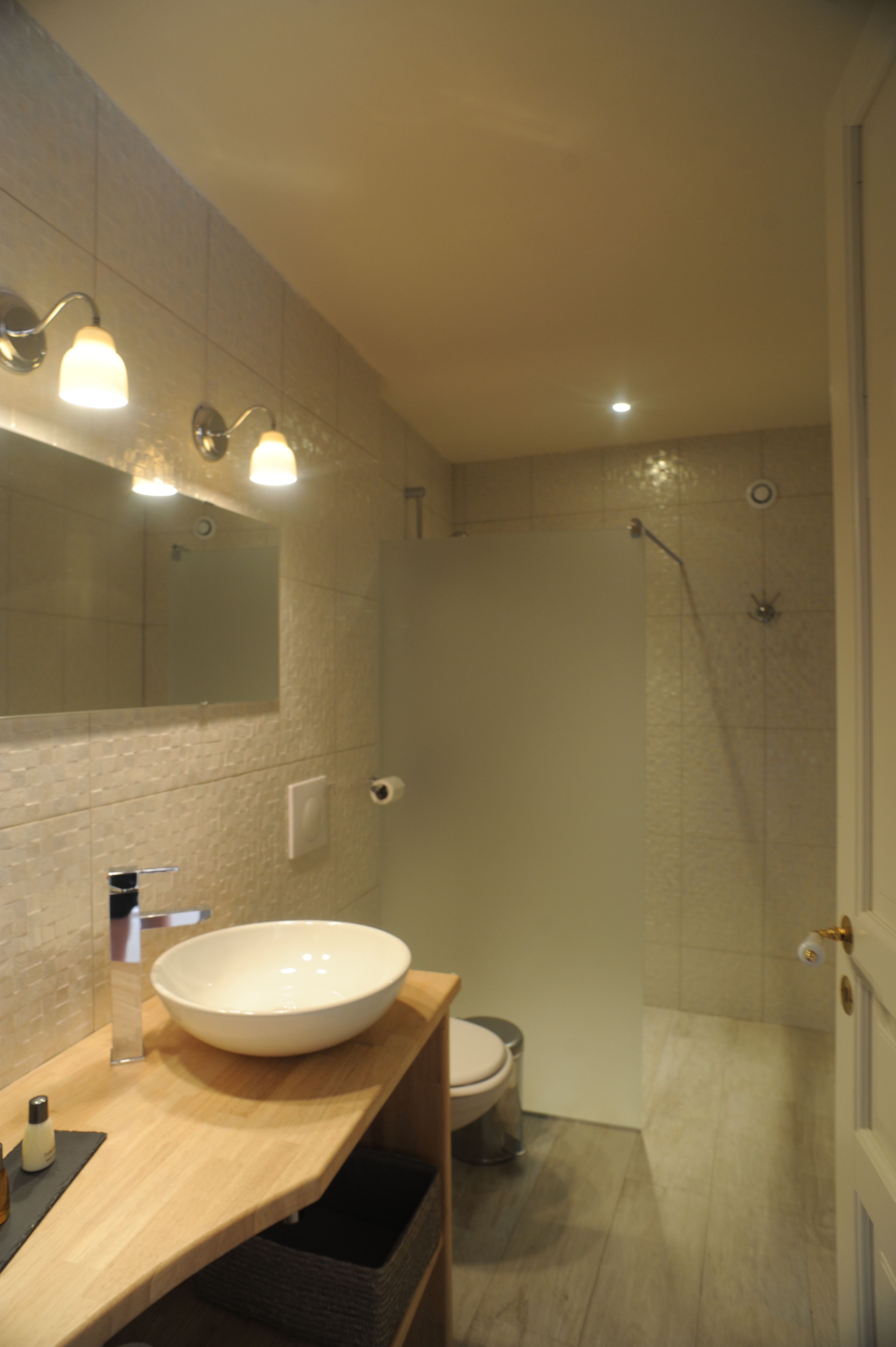 A modern bathroom with a large sink, mirror, and shower.