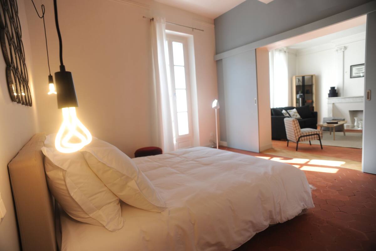 Un dormitorio con cama, una silla, un escritorio y un espejo.