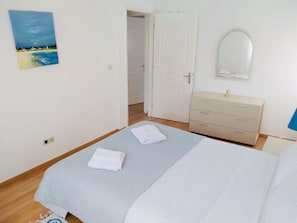 Ein Schlafzimmer mit einem Bett, einem Schminktisch, einem Spiegel und einem Bild an der Wand.