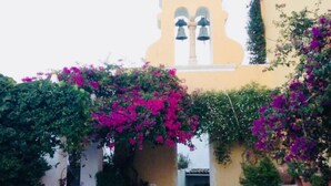 A courtyard with a bell tower, potted plants, and a tiled floor. - Villa Ampelaki (30 meters to the beach) (Corfu)
