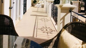 A covered outdoor area with wicker furniture and a white building with black shutters. - Villa Ampelaki (30 meters to the beach) (Corfu)