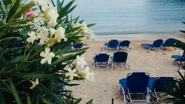 A beach with blue lounge chairs and a rocky cliff. - Villa Ampelaki (30 meters to the beach) (Corfu)