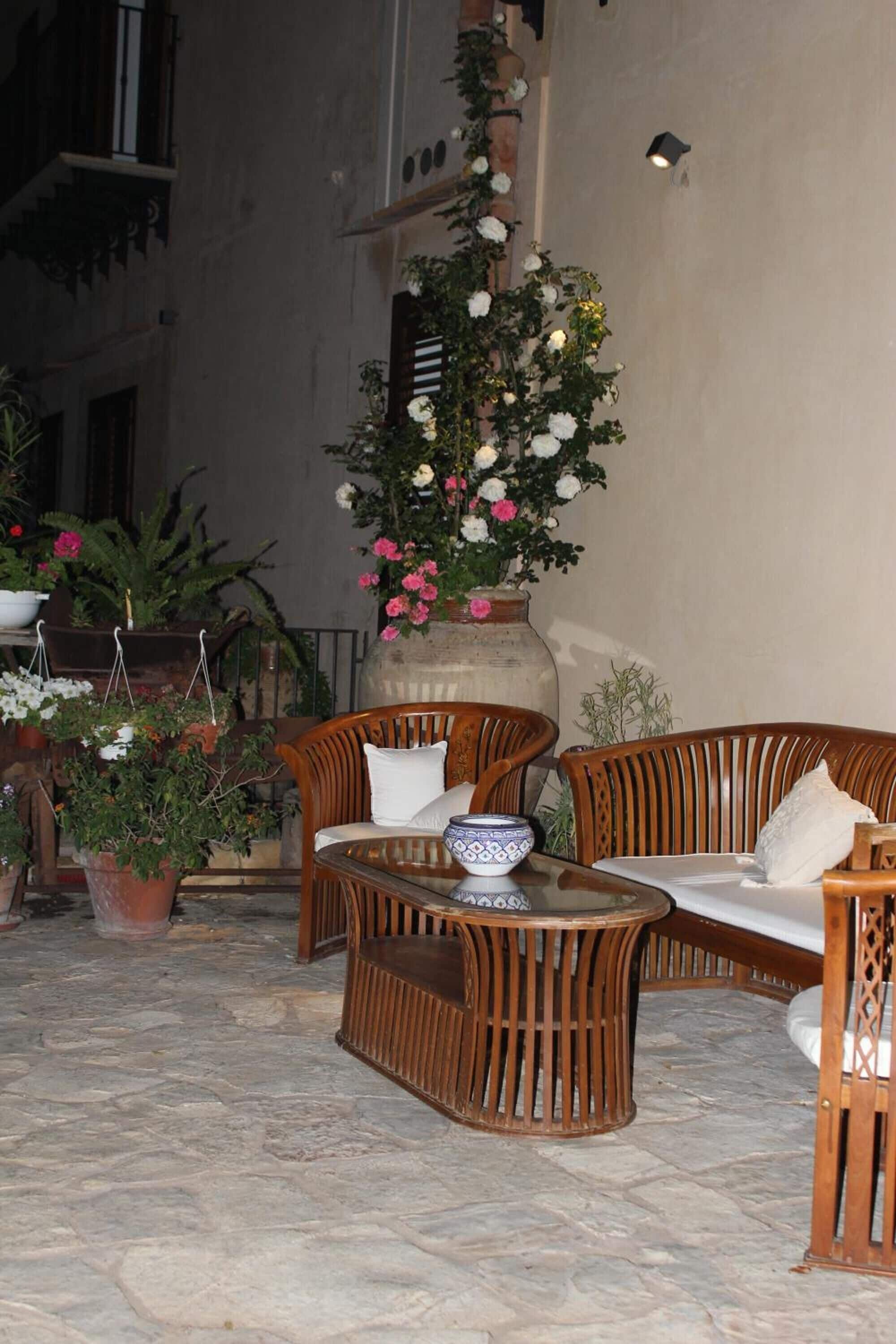 An outdoor seating area with wicker furniture, a central table, and potted plants.